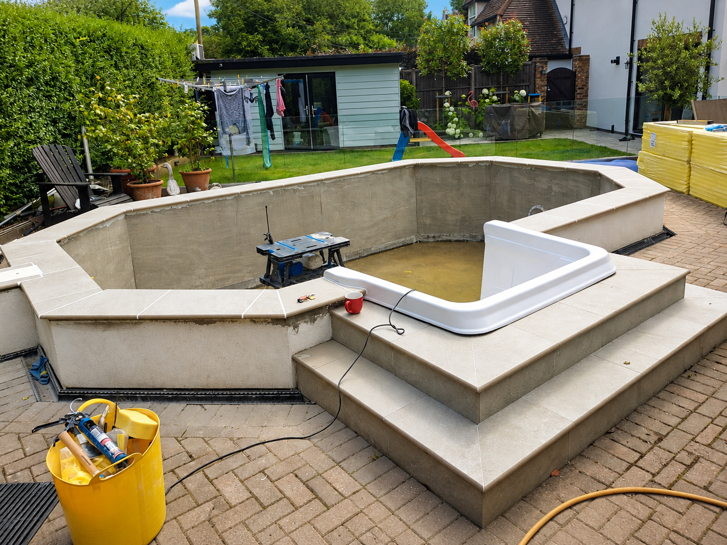 Swimming pool at coping stage with surrounding paving